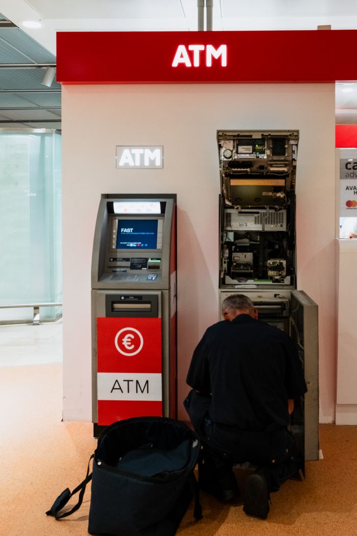 hero-img-01 A technician servicing an ATM in a Venice bank lobby. Business and security themes.
