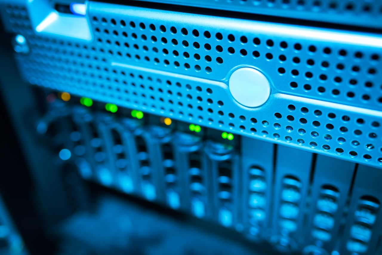 services-01 Focused view of a modern data server rack with blinking lights in a blue-lit environment.